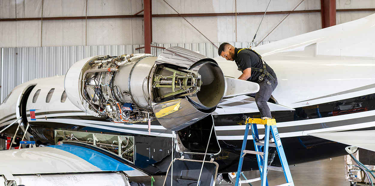 Technician on a ladder performing Citation engine work