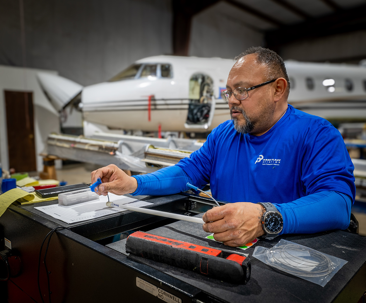 Plane Place Aviation technician at workstation reviewing maintenance records