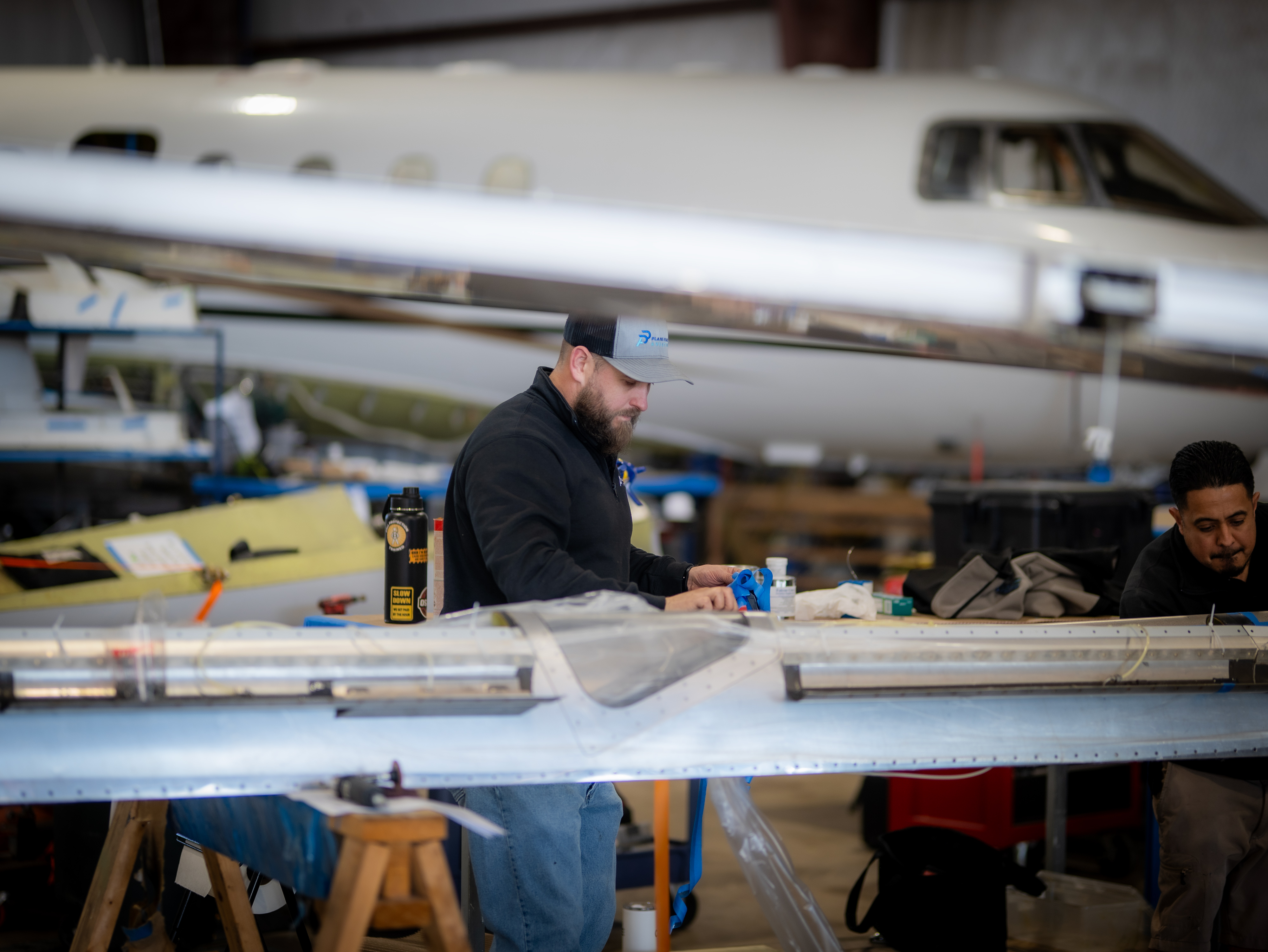 PPA technicians working on aircraft wing with business jet in background at Cleburne hangar