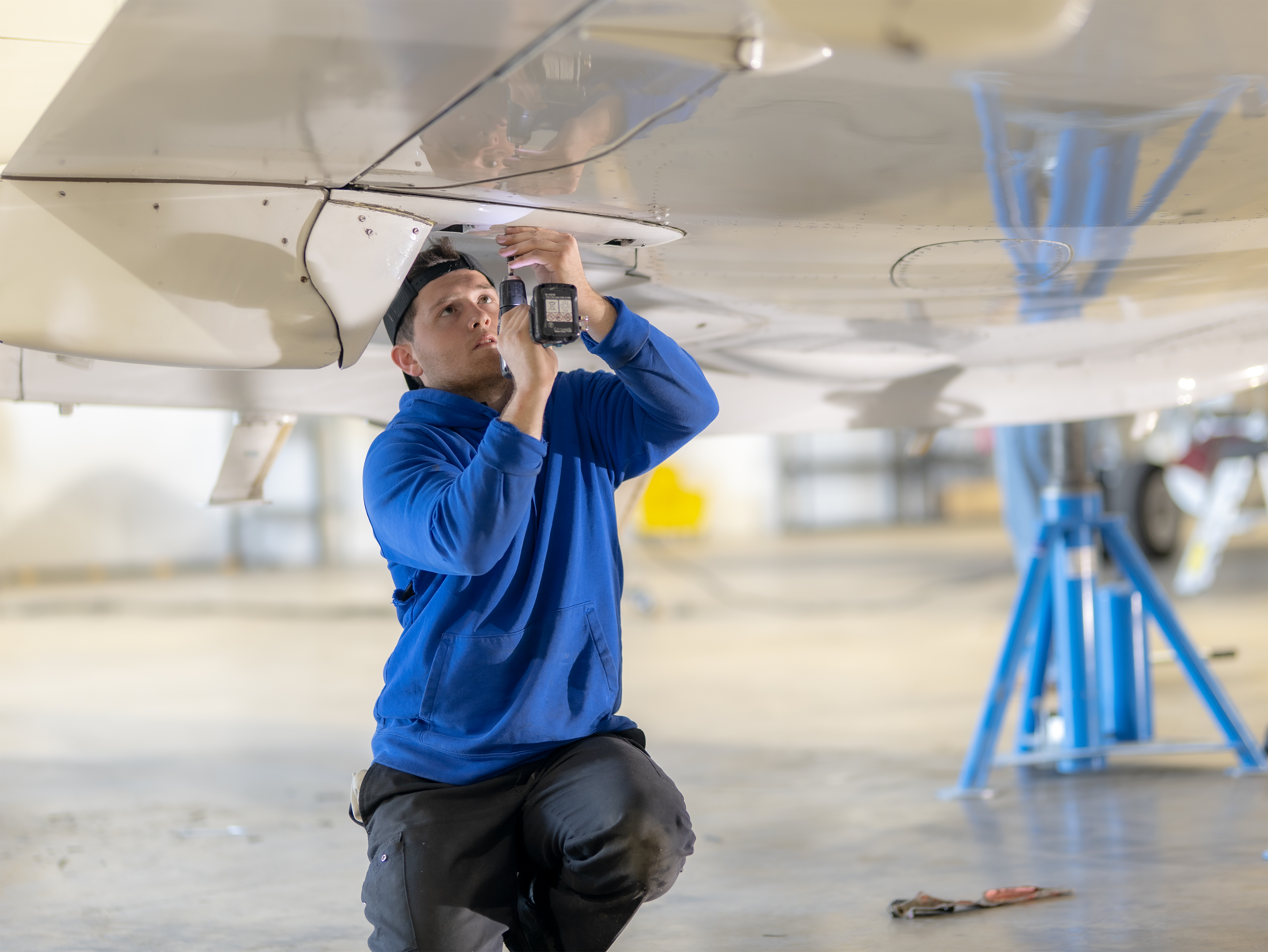 PPA technician inspecting aircraft underside in hangar