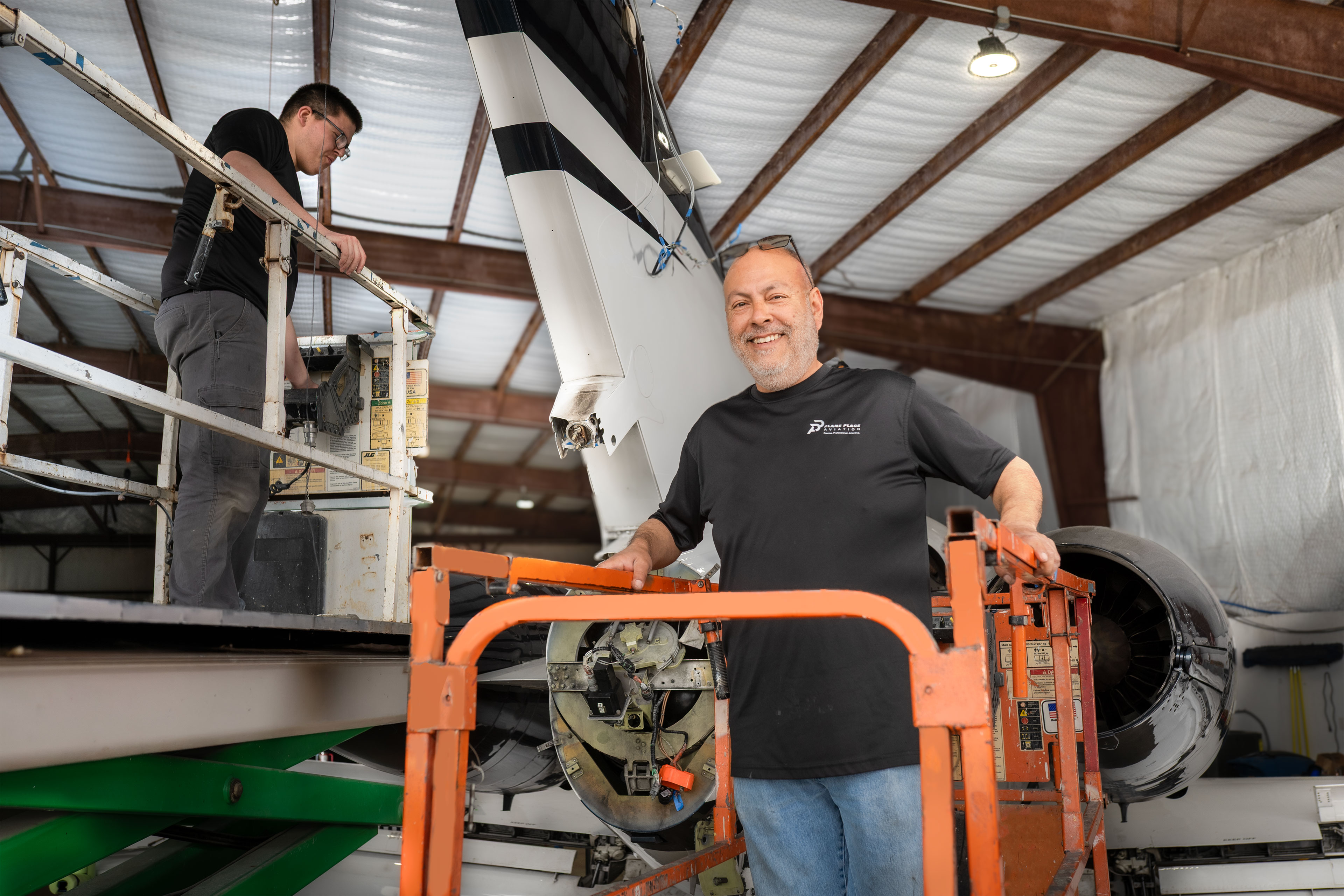 Plane Place Aviation technician on a lift working on a business jet